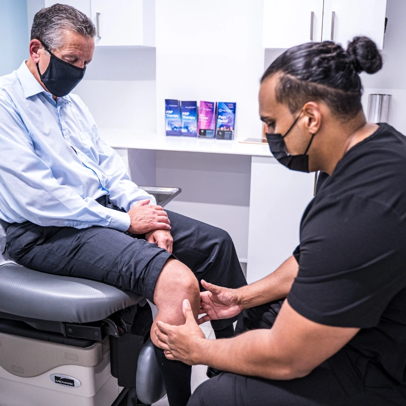 A specialist at Pain Treatment Specialists performs a physical evaluation of a patient's knee to diagnose chronic joint pain and determine a personalized treatment plan.