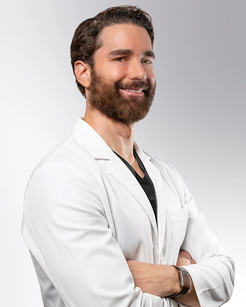 Dr. Shaun Cole, board-certified vein doctor at VIP Medical Group, smiling in a white coat with arms crossed.