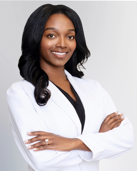 A professional portrait of a Physician Assistant at Vein Treatment Clinic. She is wearing a white medical coat and standing with her arms crossed, representing the expert and compassionate clinical team dedicated to patient care and pain relief.