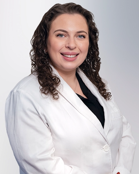 A professional portrait of a Physician Assistant at Vein Treatment Clinic. She is wearing a white medical coat and standing with her arms crossed, representing the expert and compassionate clinical team dedicated to patient care and pain relief.