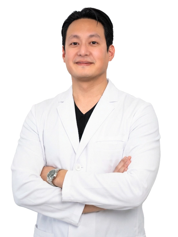 A healthcare provider stands against a neutral background, wearing a white medical coat. He has a calm and approachable expression, and his arms are gently crossed. The image conveys confidence, professionalism, and warmth suitable for a clinical