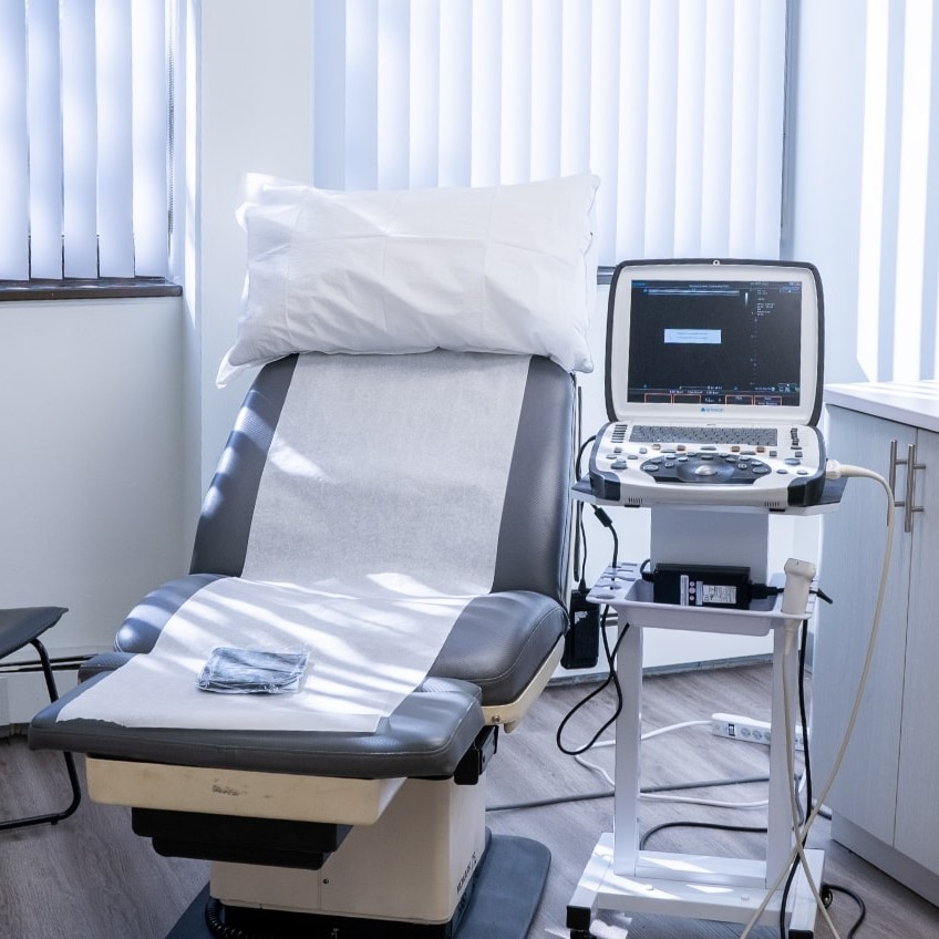 The interior of a treatment room with a comfortable clinical bed in a clean office illuminated by sun light.
