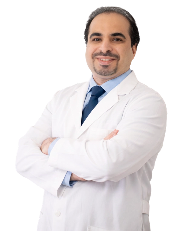 A healthcare provider stands against a neutral background, wearing a white medical coat. He has a calm and approachable expression, and his arms are gently crossed. The image conveys confidence, professionalism, and warmth suitable for a clinical setting.